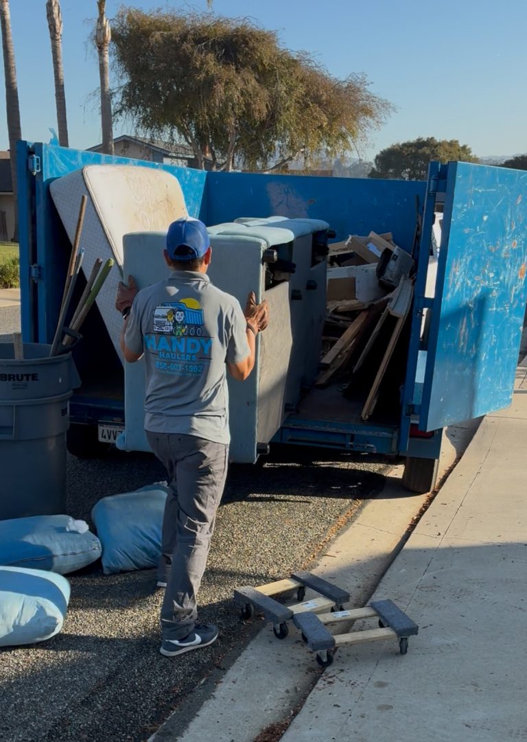 Handy Haulers team member loading a large sofa into a dump trailer for furniture removal in San Diego.
