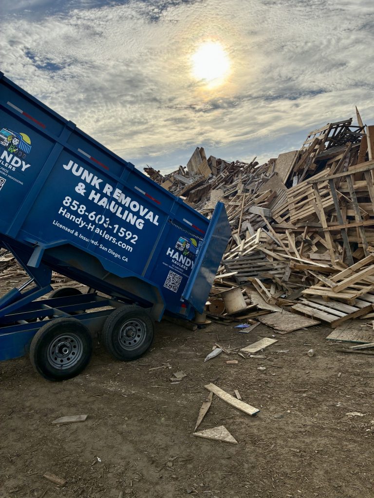 Handy Haulers dump trailer emptying wood pallets for recycling at a San Diego landfill clean wood area during sunset.