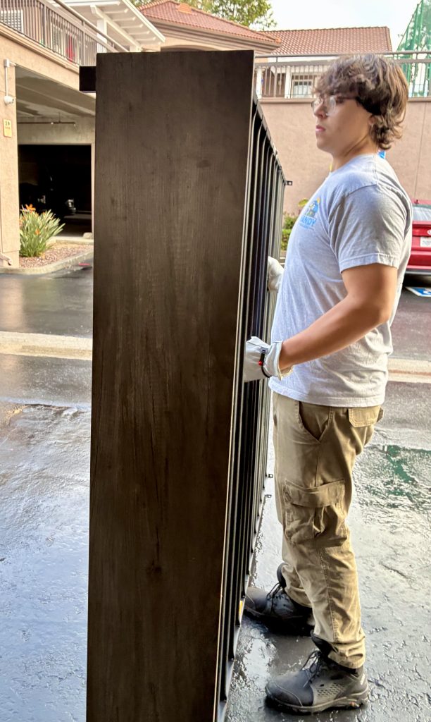 Professional junk removal: Handy Haulers employee hauling a large headboard away from a multi-family apartment complex.